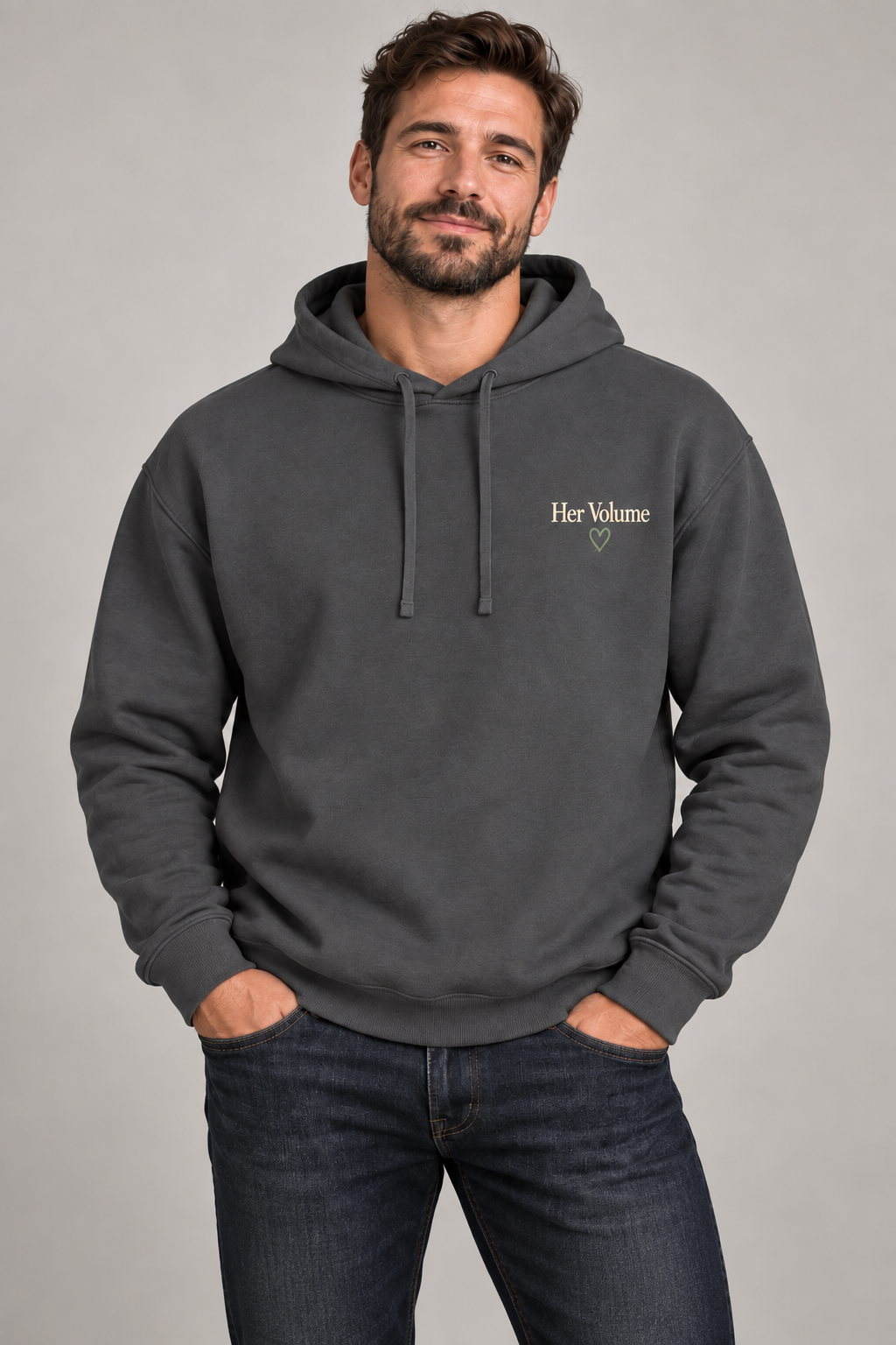 Front-view AI model mockup of Her Volume charcoal hoodie with ivory logo and sage heart.